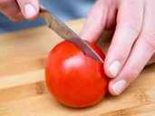1. Mit einem Messer die Tomate auf der Unterseite kreuzweise einritzen. Foto: Andrea Warnecke/dpa-tmn 1. Mit einem Messer die Tomate auf der Unterseite kreuzweise einritzen. Foto: Andrea Warnecke/dpa-tmn