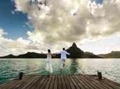 Ein junges Ehepaar springt von einem hölzernen Pier in das wunderbare Meer von Bora Bora in Französisch-Polynesien. Ein junges Ehepaar springt von einem hölzernen Pier in das wunderbare Meer von Bora Bora in Französisch-Polynesien.